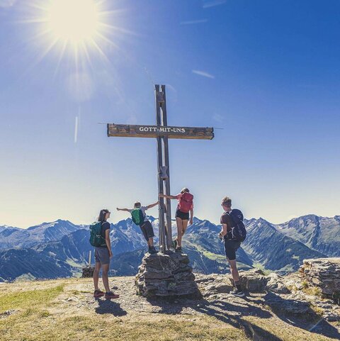 Eine Familie steht bei einem Gipfelkreuz