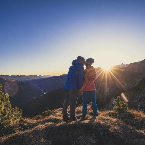 Ein Mann und eine Frau küssen sich vor einem Sonnenaufgang