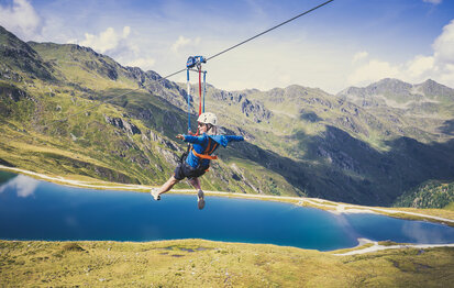 Eine Frau fährt mit einer Zipline über der traumhaften Natur